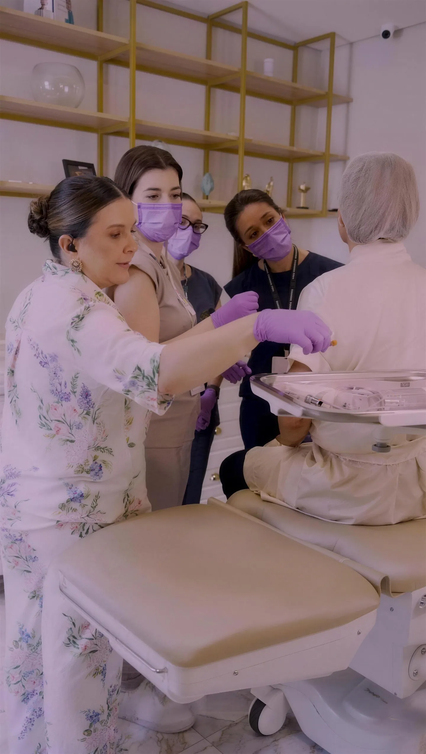 Dra. Karine Braga e equipe, de máscaras lilás, atendendo uma paciente na cadeira da IKB Clinic